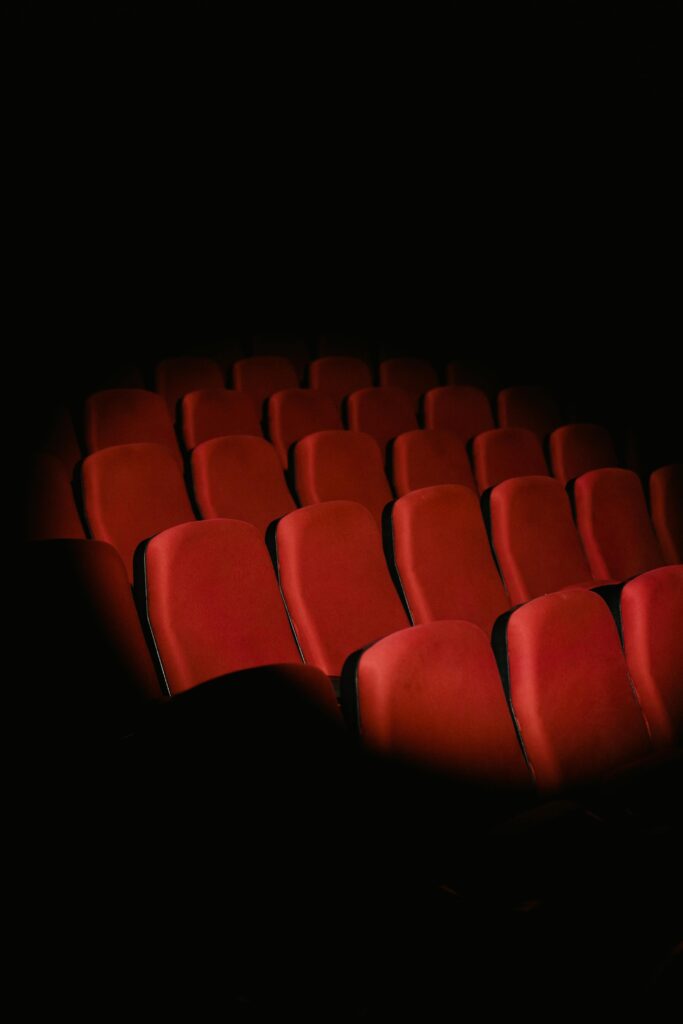 Rows of empty red seats in a dark movie theater creating a moody atmosphere.